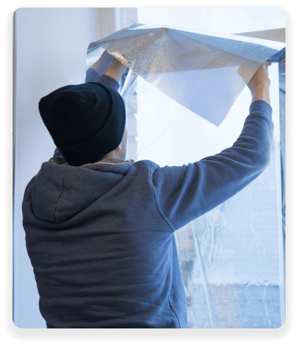 Installer smoothing a sheet of window film onto a large pane of glass
