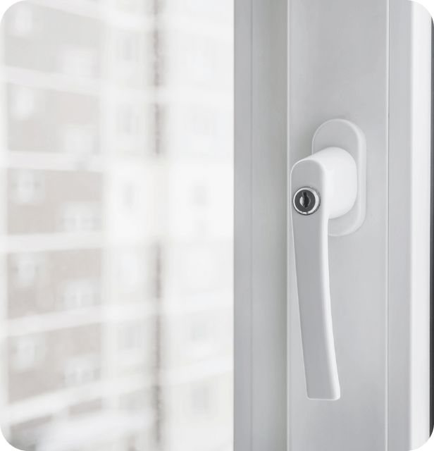 Close-up of a white window frame and its locking handle, with a building visible through the glass