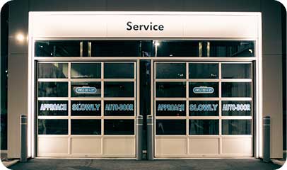 Glazed service-bay doors at a lit building entrance