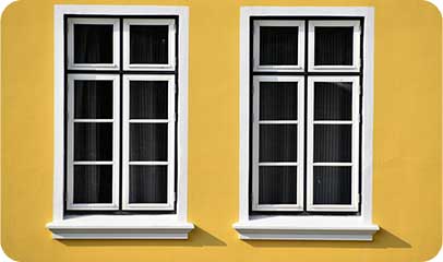 Two white-framed windows set into a yellow exterior wall