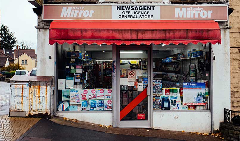 Corner shop front with a red awning and full-height glazed display windows
